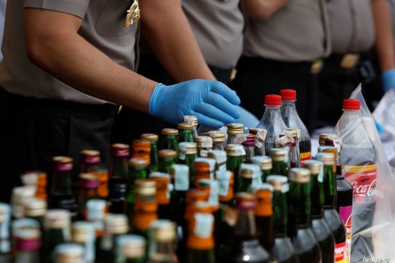 Police prepare evidence during a press conference regarding the arrests of suspects linked to the production and sale of illegal bootleg alcohol which claimed the lives of more than 80 people this week in Jakarta