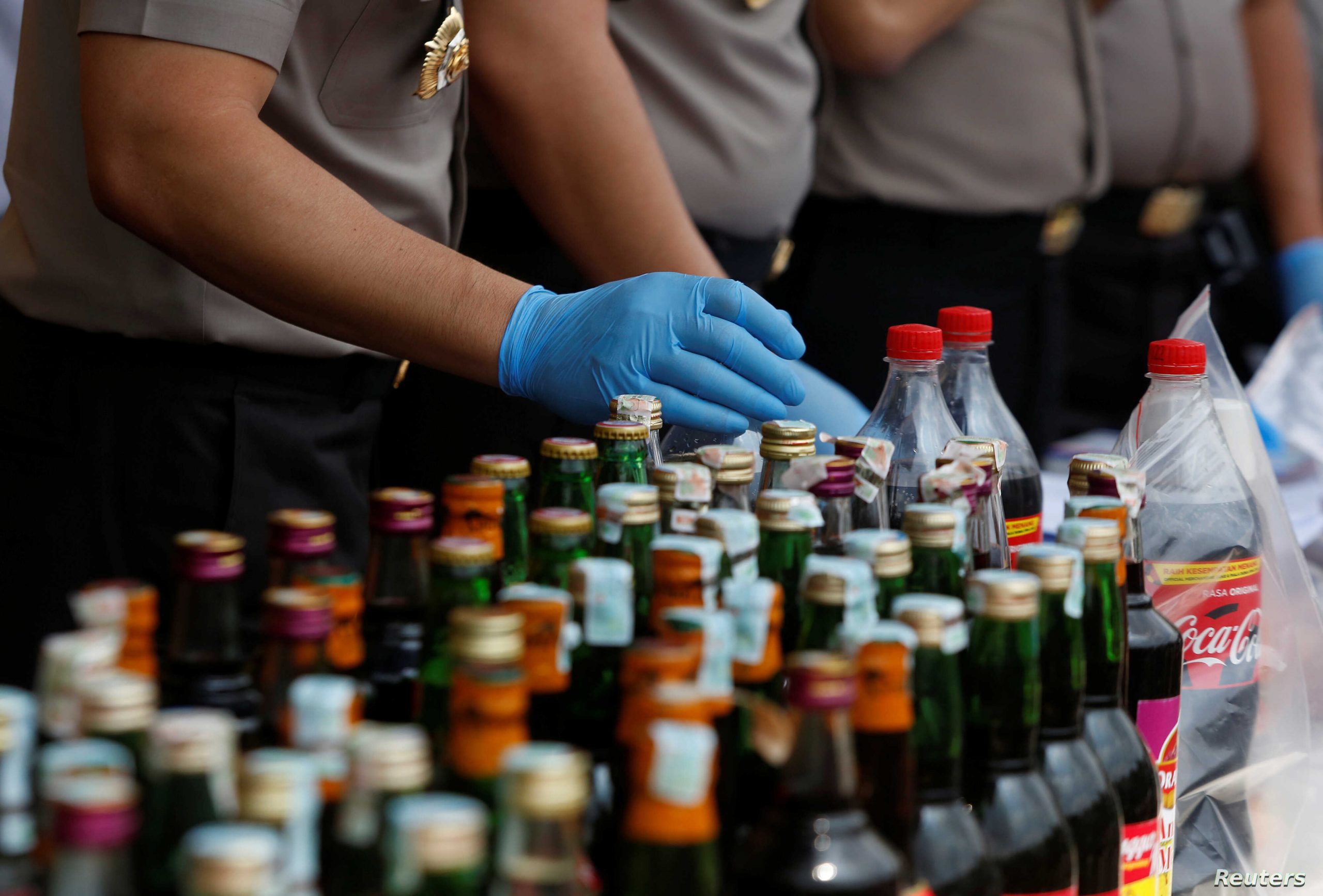 Police prepare evidence during a press conference regarding the arrests of suspects linked to the production and sale of illegal bootleg alcohol which claimed the lives of more than 80 people this week in Jakarta